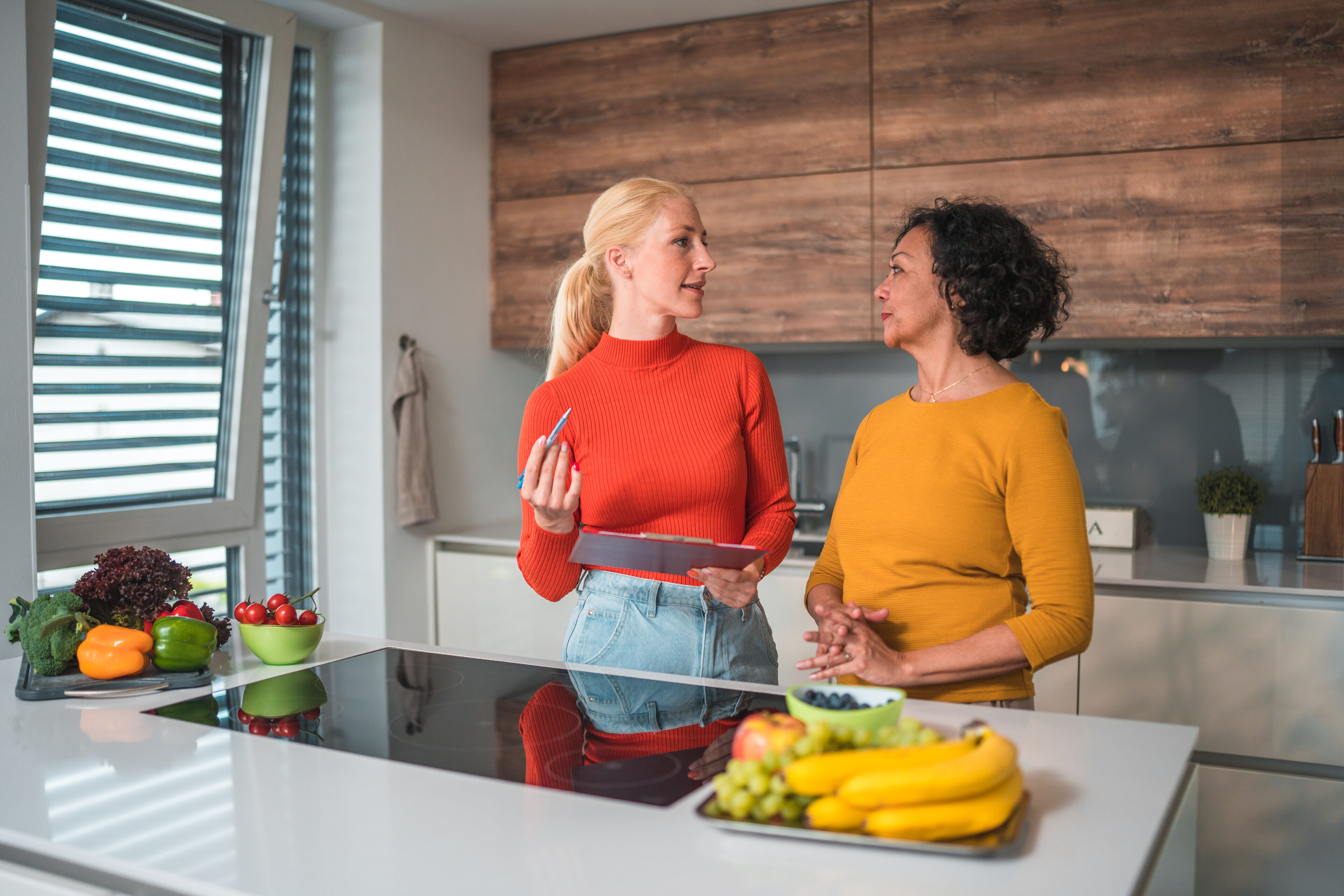 Two women talking in modern kitchen.