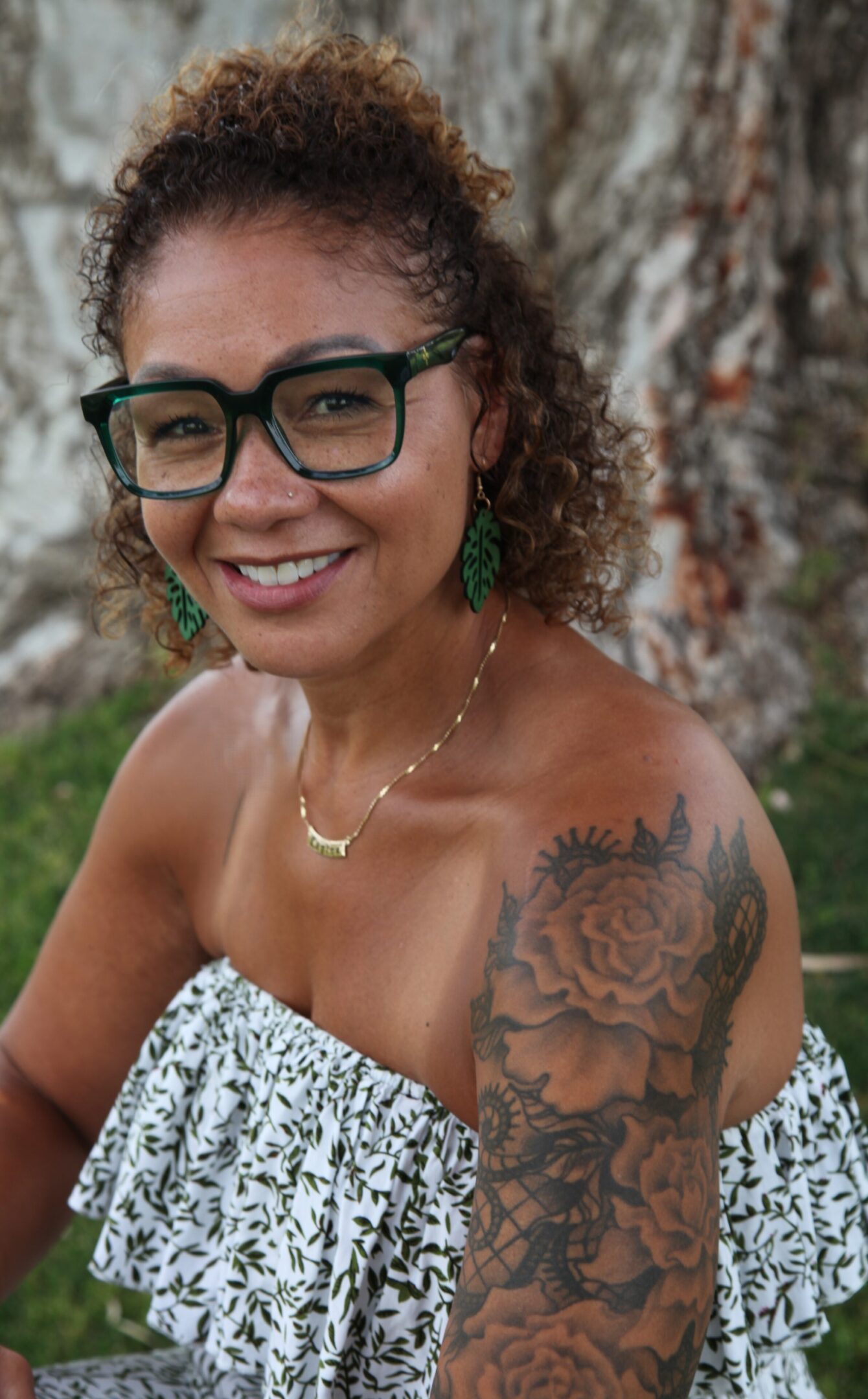 A woman with glasses and tattoos on her shoulder.